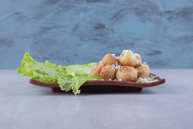 Fried potatoes and lettuce on brown plate. 