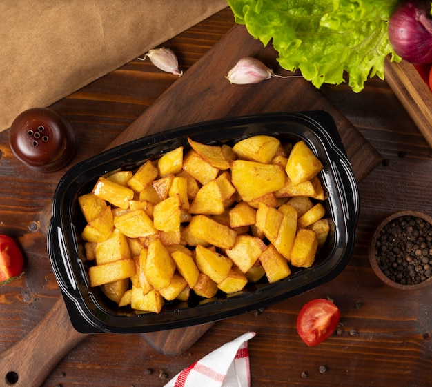 Foto gratuita patate fritte con erbe da asporto in contenitore nero.