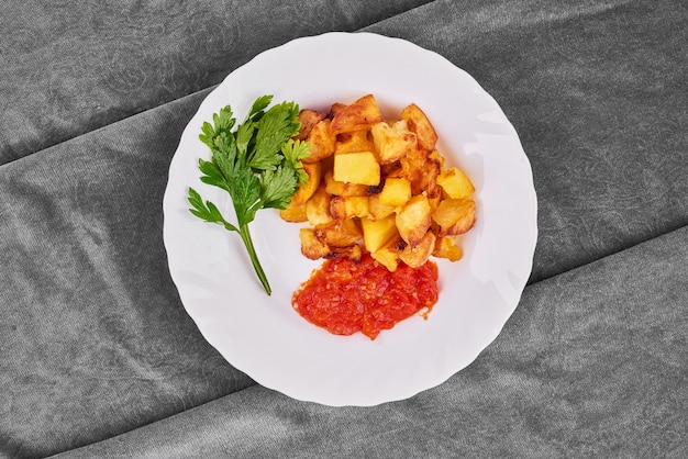Fried potatoes with tomato paste and herbs.
