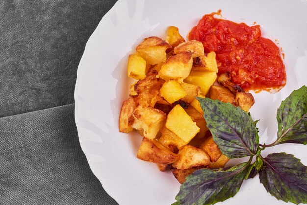 Fried potatoes with tomato sauce and basilic.