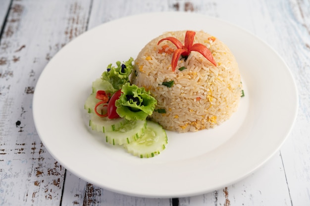Fried rice with eggs in a white plate on wood surface