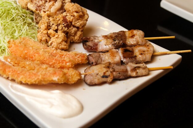 Fried and roasted meat pieces and cut cabbage served on a white plate