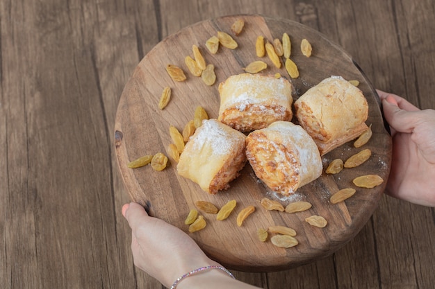 Fried roll cookies with white raisins and sweet stuffings on a wooden board.