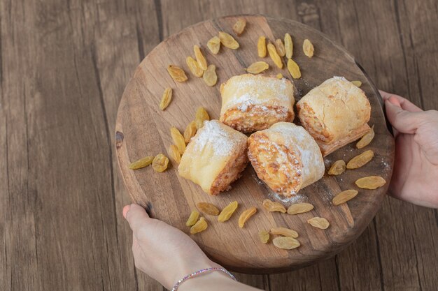 Fried roll cookies with white raisins and sweet stuffings on a wooden board.