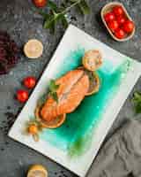 Бесплатное фото Жареный лосось с дольками лимона и помидорами