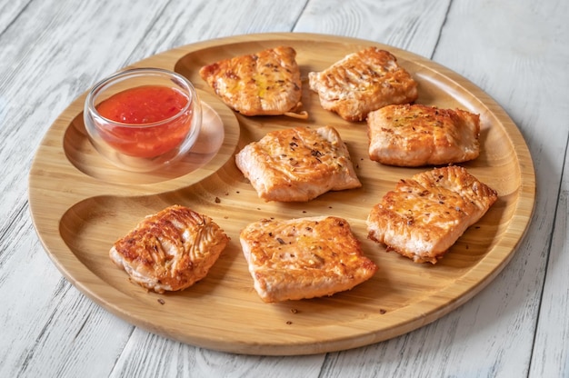 Fried salmon with sauce on the wooden serving tray