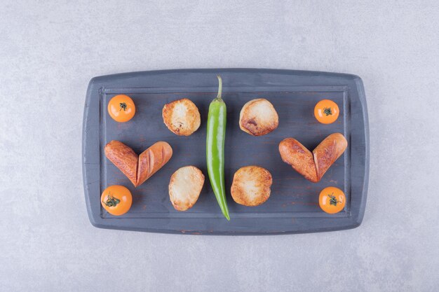 Fried sausages and potatoes on dark board. 