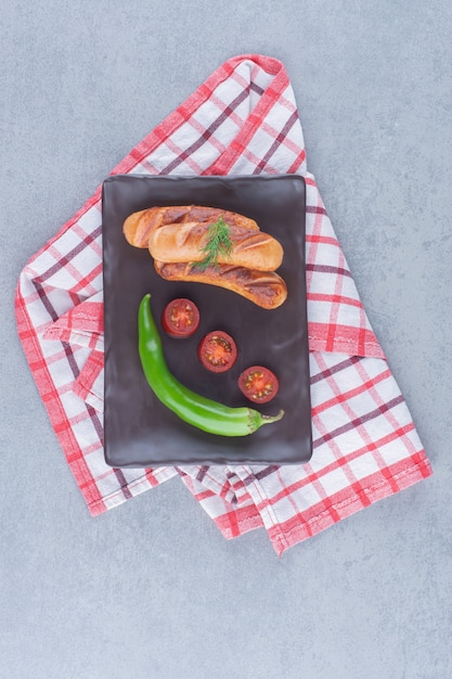 Fried Sausages with vegetables on black board. 