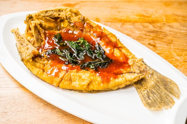 Fried sea bass fish in white plate with spicy and sweet sauce