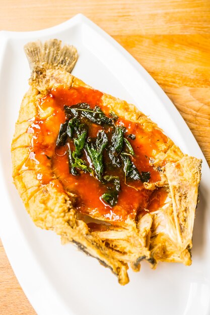 Fried sea bass fish in white plate with spicy and sweet sauce