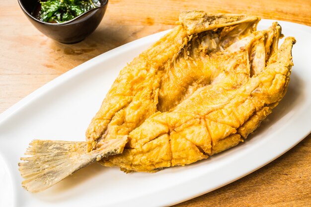 Fried sea bass fish in white plate with spicy and sweet sauce