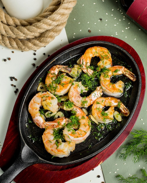 Free photo fried shrimps in garlic and herbs sauce garnished with dill