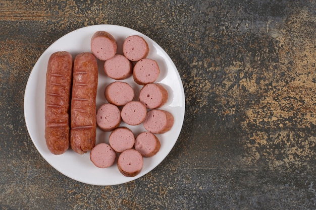 Free photo fried sliced sausages on white plate.