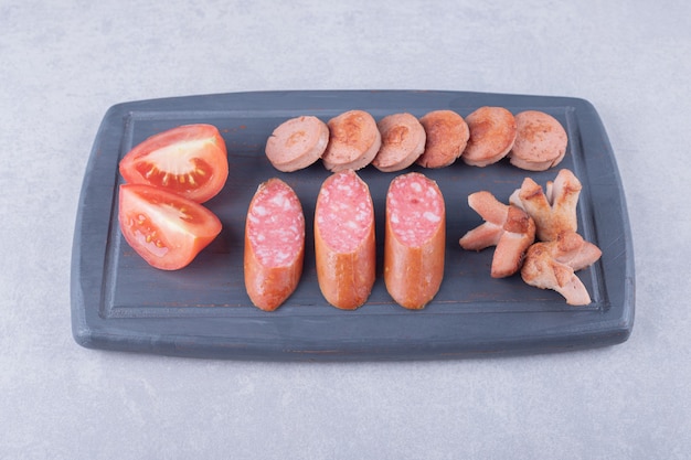 Fried and smoked tasty sausages on dark board. 