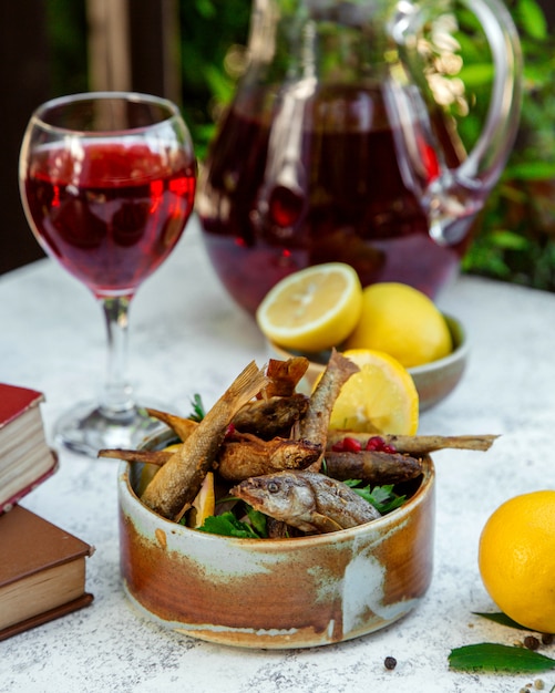 Free photo fried sprats with lemon and herbs and a glass of juice