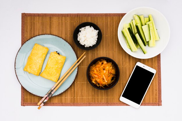 揚げ春巻き。サラダ;ご飯とプレースマットの上に携帯電話でスライスしたズッキーニ