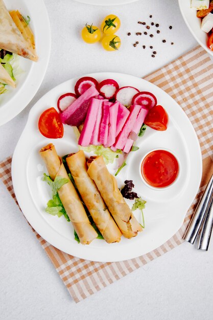 fried spring rolls with sauce and vegetables on the table