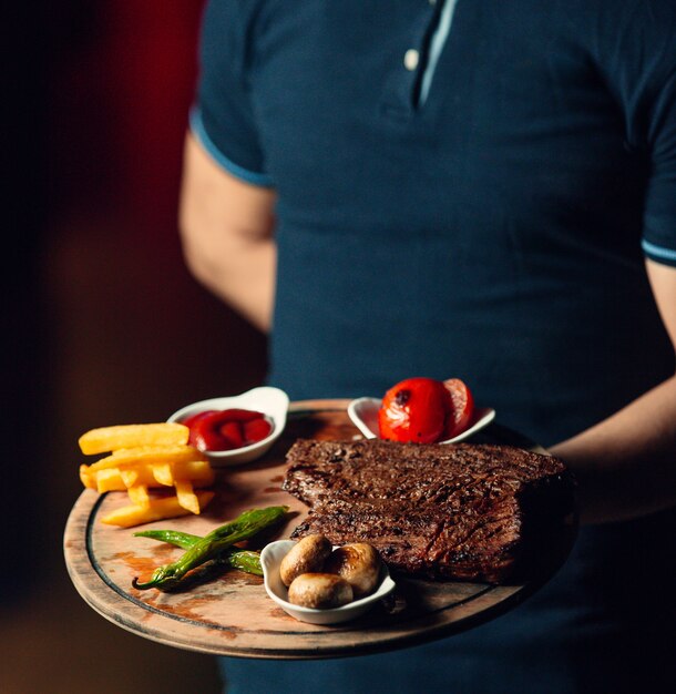 Fried steak with french fries on wooden board