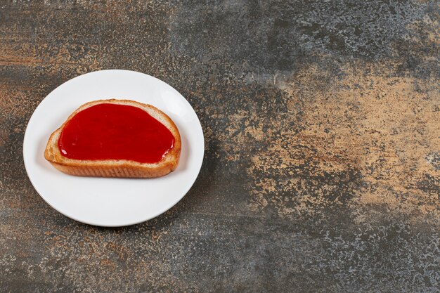 Fried toast with strawberry jam on white plate.