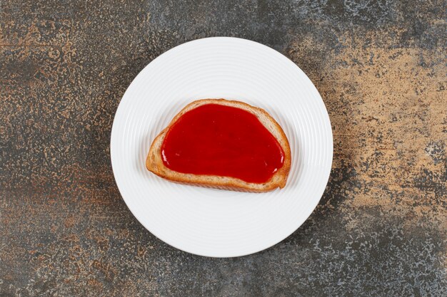 Fried toast with strawberry jam on white plate.