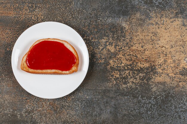 Fried toast with strawberry jam on white plate.