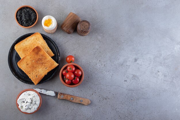 Fried toasts with butter and red fresh cherry tomatoes placed on background.