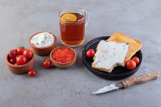 Fried toasts with butter and red fresh cherry tomatoes placed on marble. 