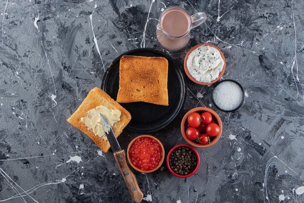 신선한 빨간 체리 토마토와 튀긴 토스트는 대리석 테이블에 배치됩니다.