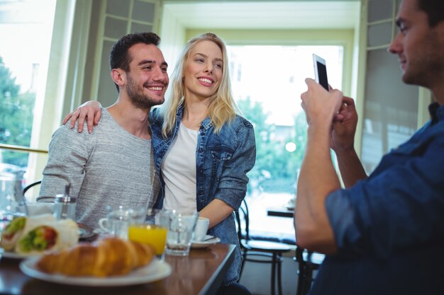 Friend clicking photos of couple from mobile phone