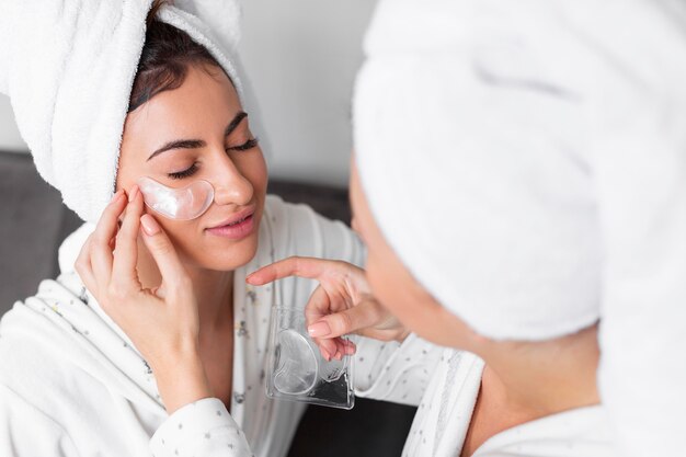 Friend helping woman apply under eye patch