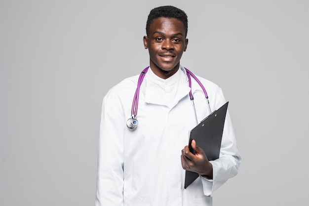 Friendly Afro-American doctor holding a clipboard and smiling at the camera isolated on gray background