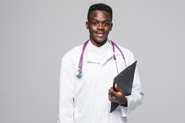 Friendly Afro-American doctor holding a clipboard and smiling at the camera isolated on gray background
