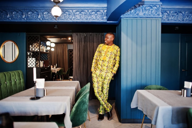 Friendly afro man in traditional yellow clothes at restaurant
