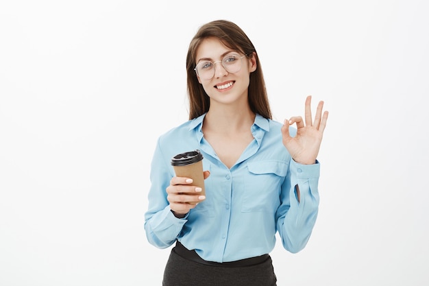 Friendly brunette businesswoman posing in the studio with her coffee