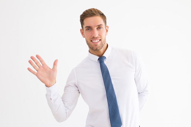 Friendly business man waving with hand and looking at camera