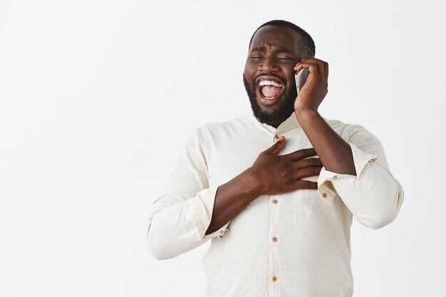 Friendly cheerful young guy posing against the white wall