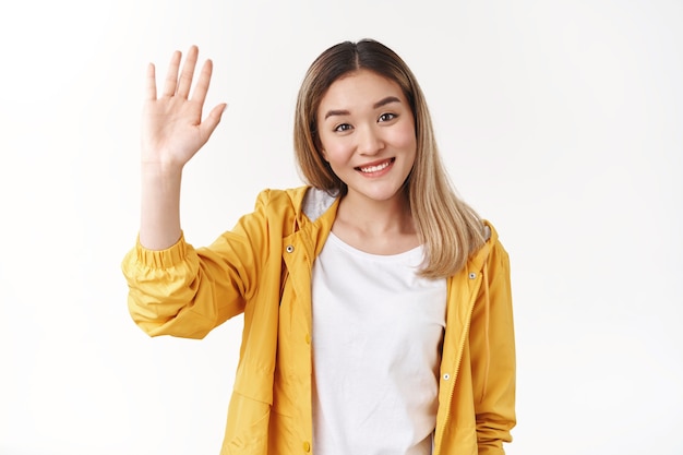 Дружелюбная милая жизнерадостная общительная азиатская белокурая девушка поднимите руку, дай пять хочу поздороваться, приветствую радостно улыбаясь широко зубастая позитивная улыбка приветствуя членов команды представиться