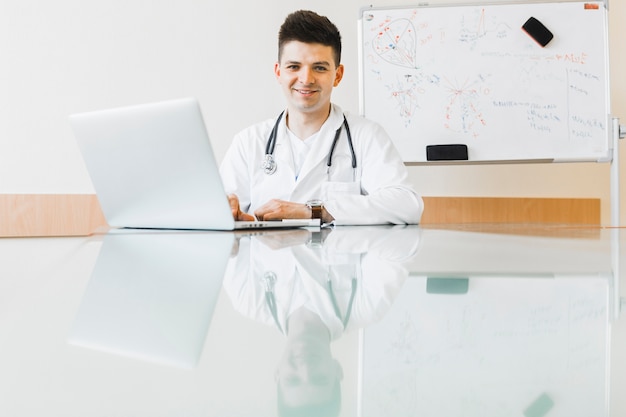 Free photo friendly doctor working with laptop