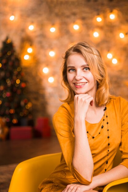 Friendly elegant woman in room with christmas lights
