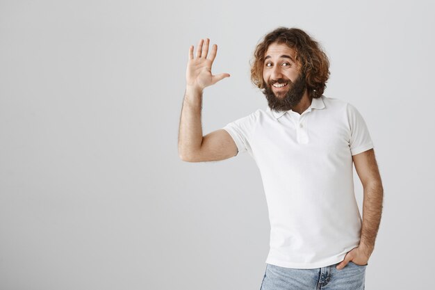 Friendly handsome middle-eastern man saying hi, waving hand in greeting gesture