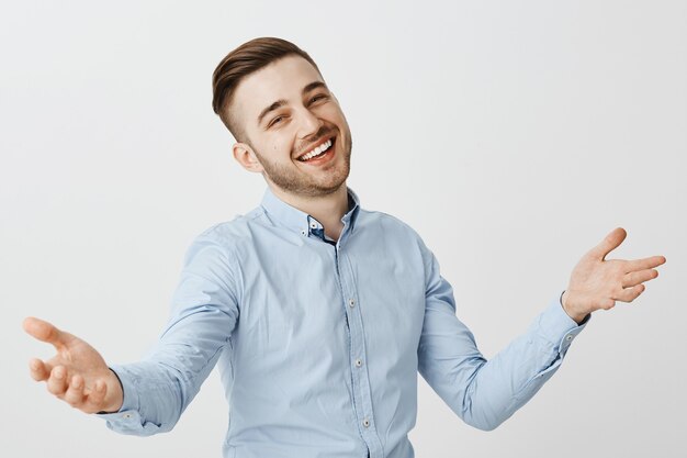 Friendly happy businessman greeting new employees, raising hands up in warm welcome