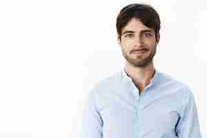 Free photo friendly-looking optimstic and handsome mature and masculine male with blue eyes and bristle smiling joyfully as standing casually in blue shirt against gray wall