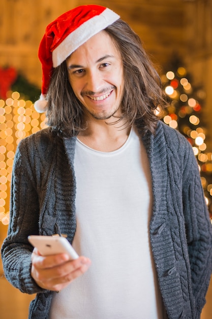 クリスマスのスマートフォンを持つフレンドリーな男