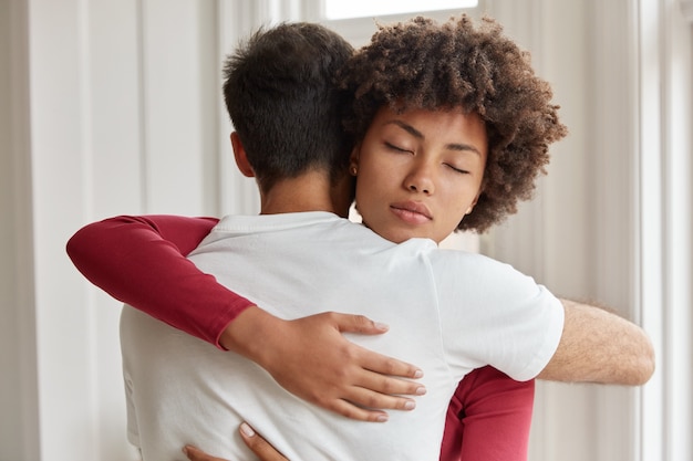 Foto gratuita fratello e sorella amichevoli di razza mista si abbracciano, si sostengono in situazioni di vita difficili, posano al chiuso, esprimono buone relazioni, esprimono amore. coppia romantica interrazziale si incontra a casa