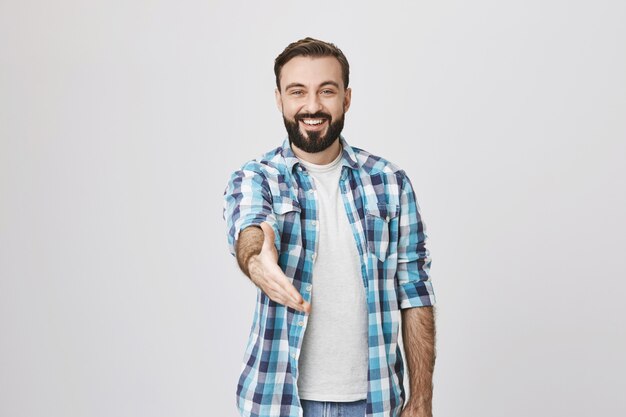 Friendly smiling guy extend hand for handshake, greeting gesture