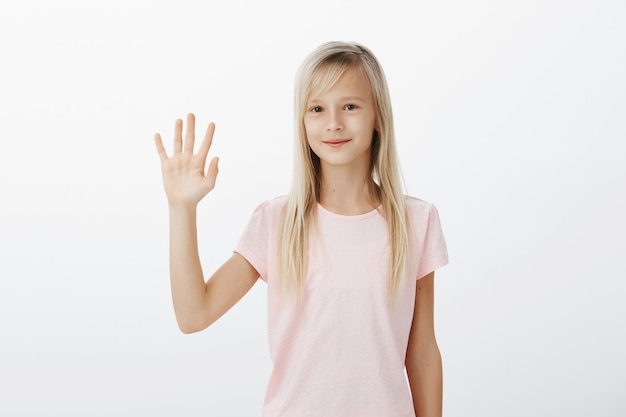 Friendly smiling kid saying hello, little woman waving hand say hi