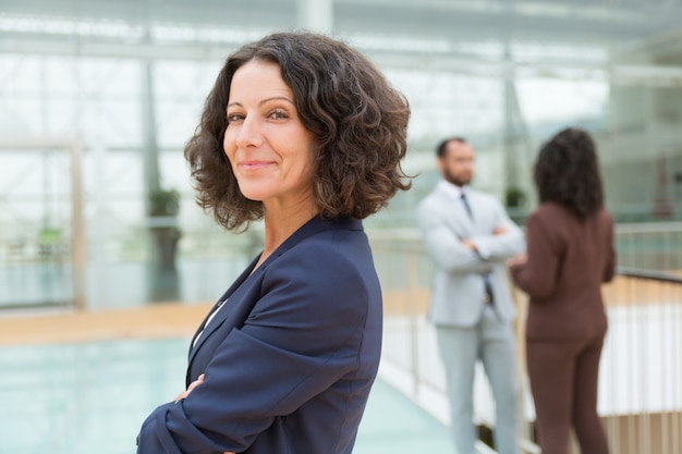 Friendly successful business woman posing with arms crossed