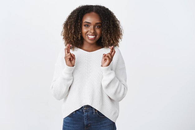 Friendly supportive africanamerican woman afro hairstyle wear sweater cross fingers good luck smiling optimistic faithfully waiting wish come true hopeful girl dream big fulfill desire