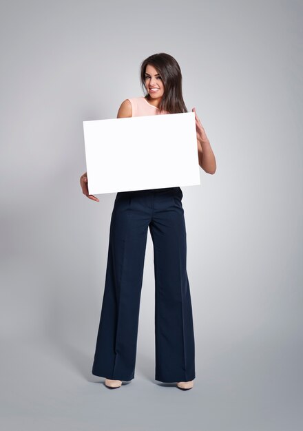 Friendly woman holding empty board