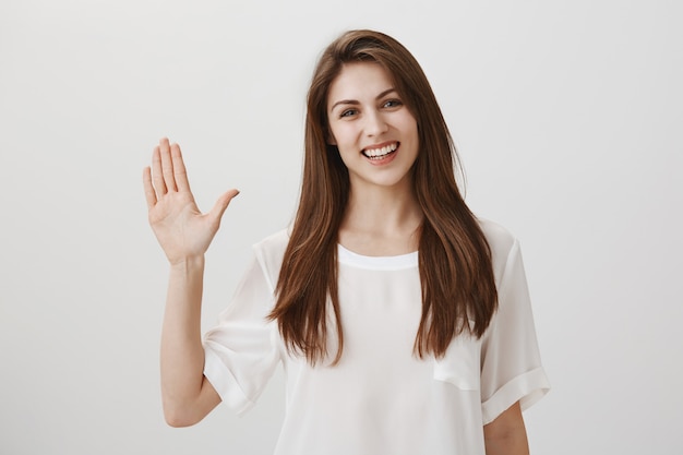Friendly woman waving hand to say hi, greeting guest